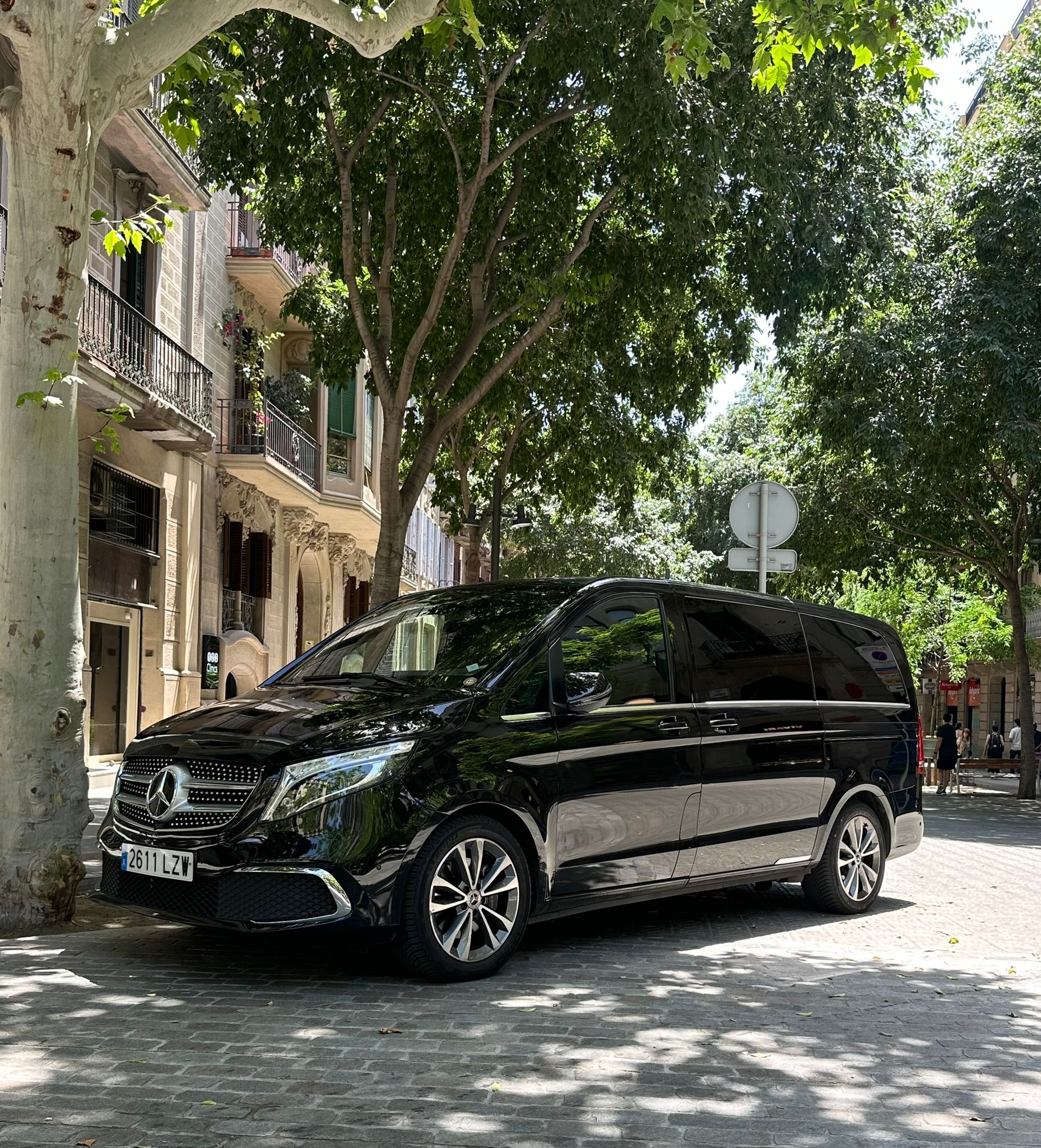 A Mercedes-Benz V-Class waiting on a tree-lined Eixample street in Barcelona